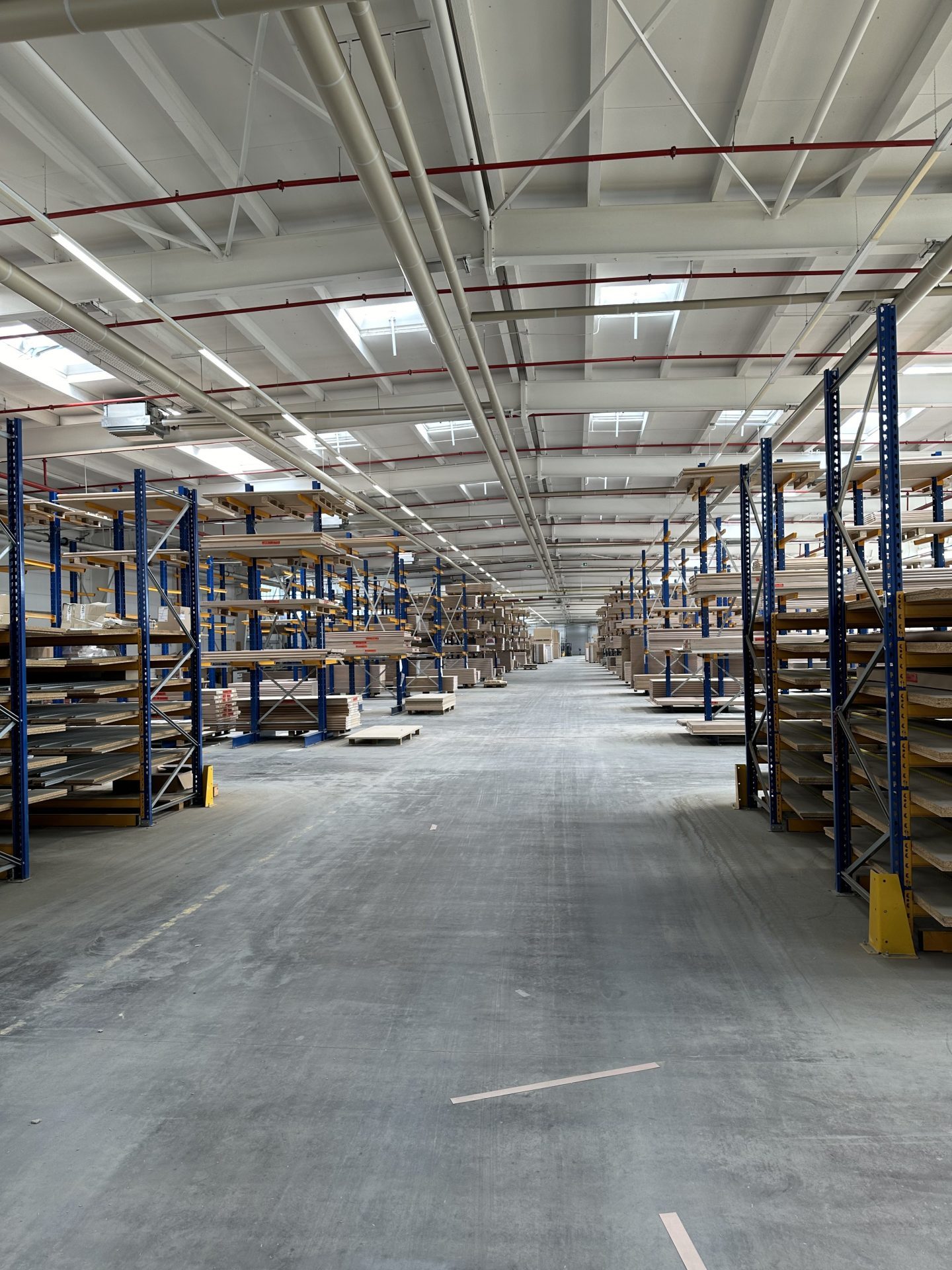 Cantilever racking holding stacked boards and long goods along a wide warehouse aisle