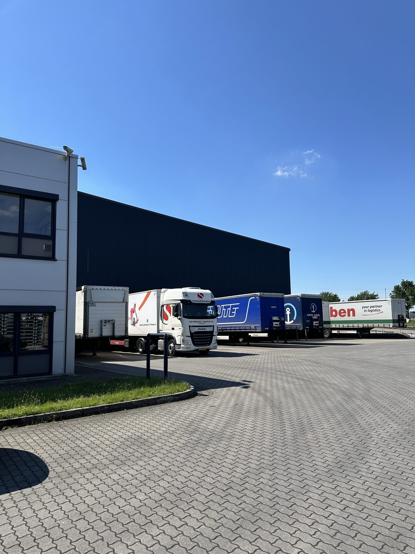 Tractor unit and trailers from various hauliers alongside the warehouse in Hünxe