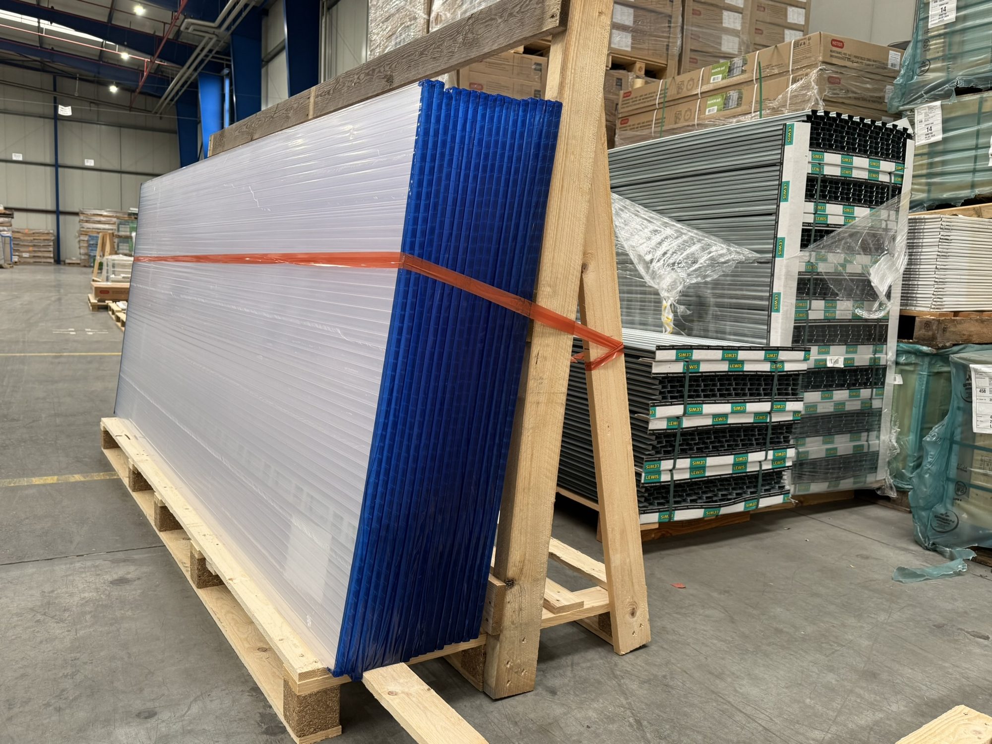 Twin-wall sheets and metal profiles, wrapped and secured in a timber frame ready for dispatch