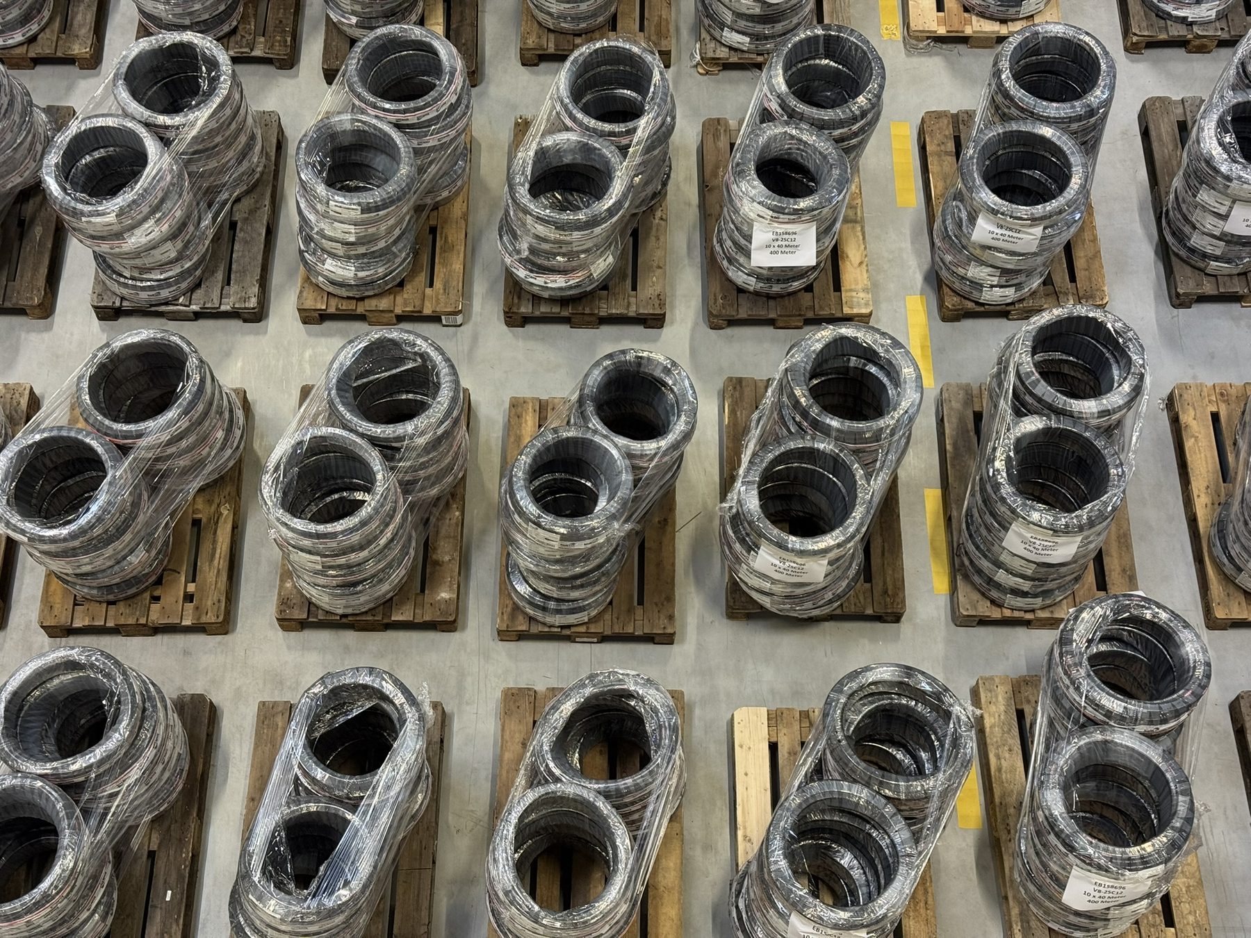 Coiled hose goods, wrapped and individually palletised, in rows across the hall floor