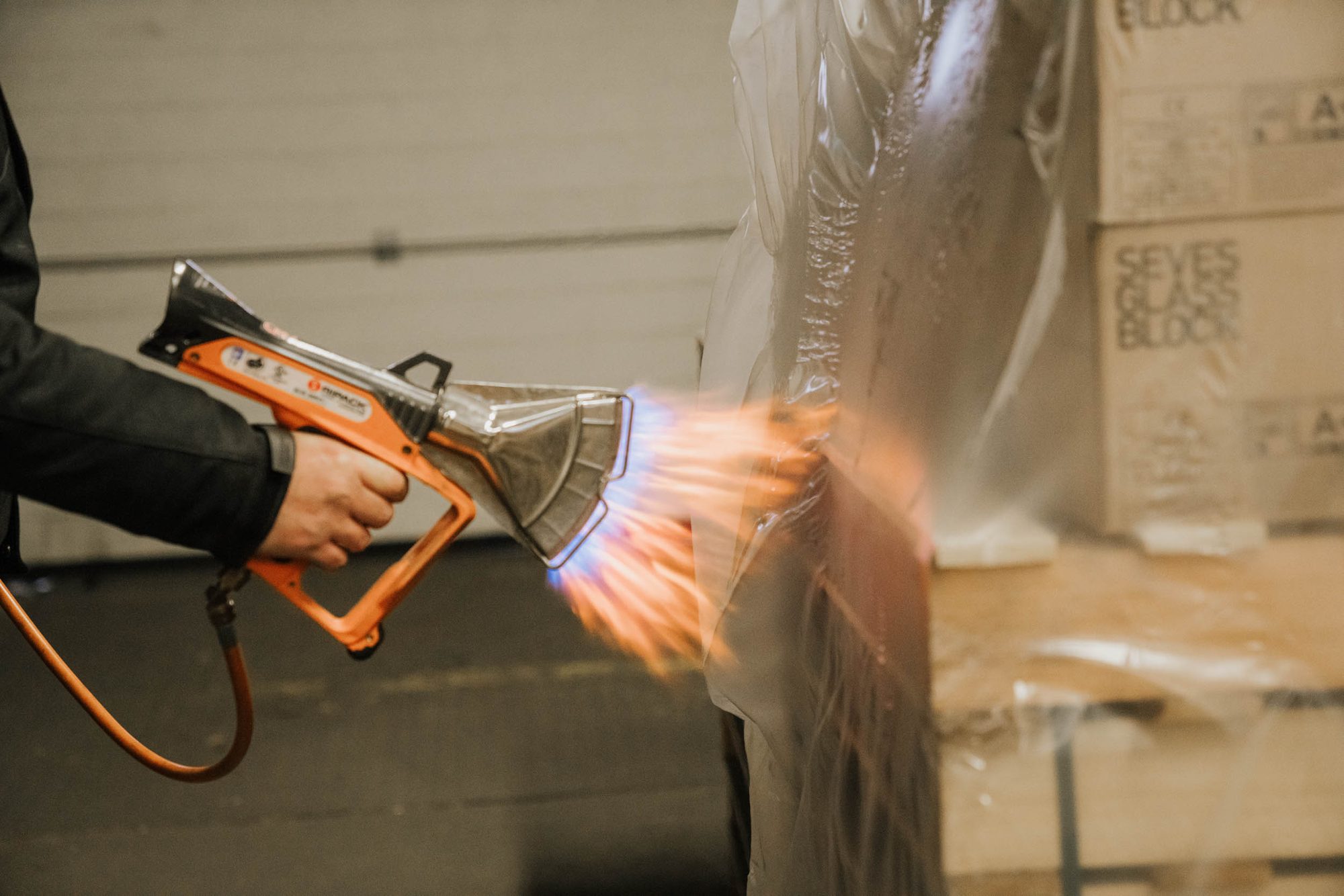 Shrink hood being sealed onto a pallet with a hot-air gun